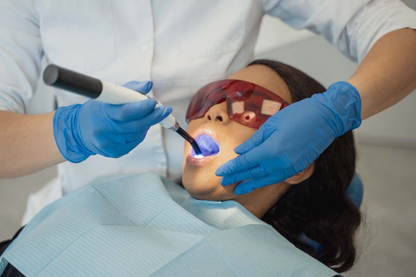 Zahnarzt härtet zahnfarbene Füllung mit UV-Licht