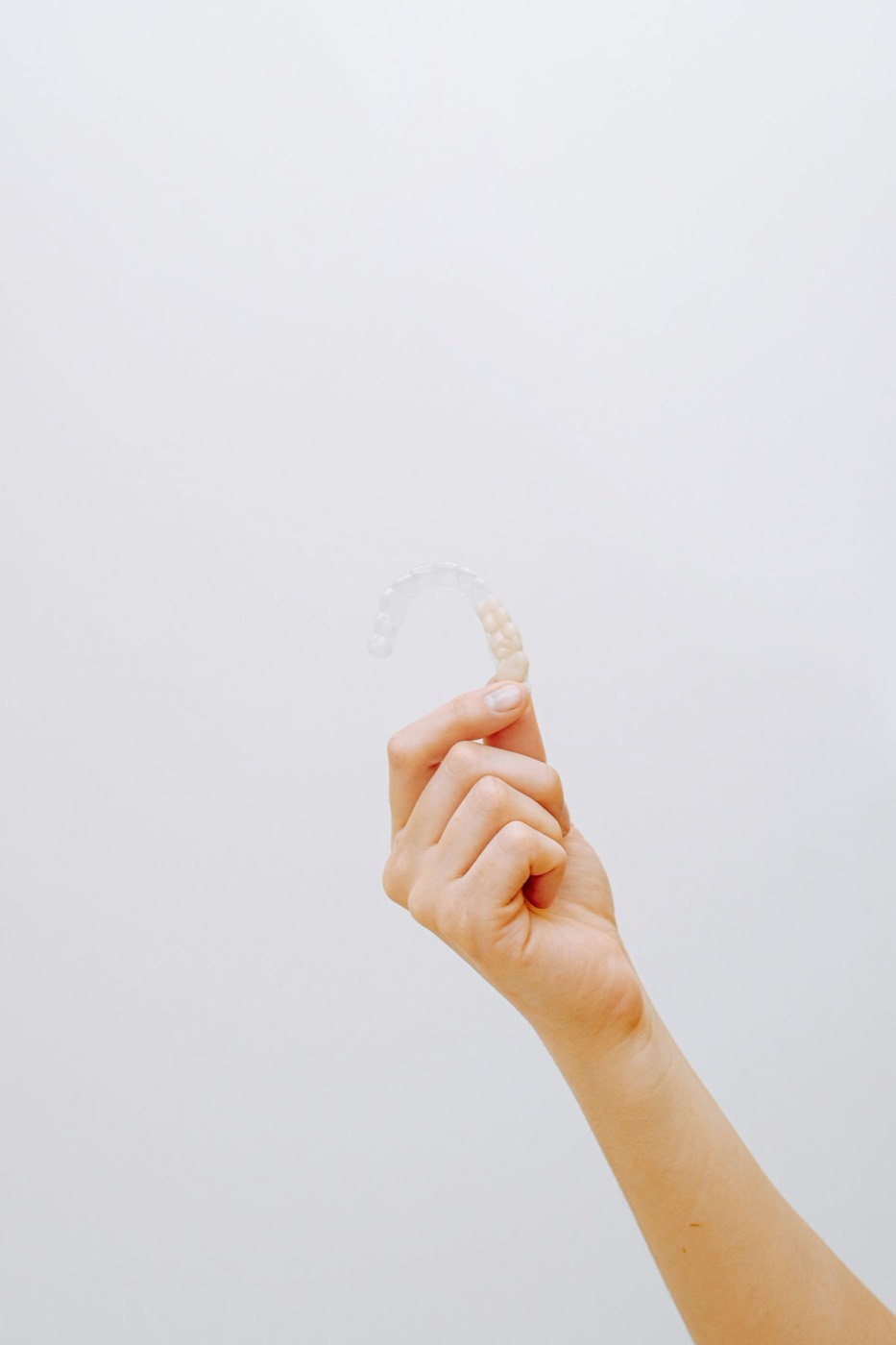 Hand hält transparente Zahnschiene (Aligner) – Kieferorthopädie in 1090 Wien