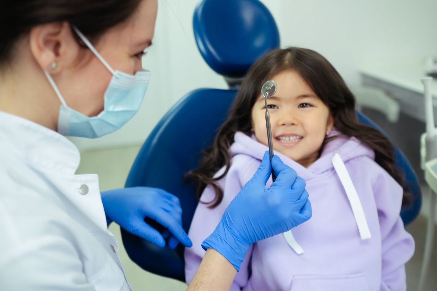 Zahnärztin mit lächelndem Kind bei der Kinderzahnbehandlung