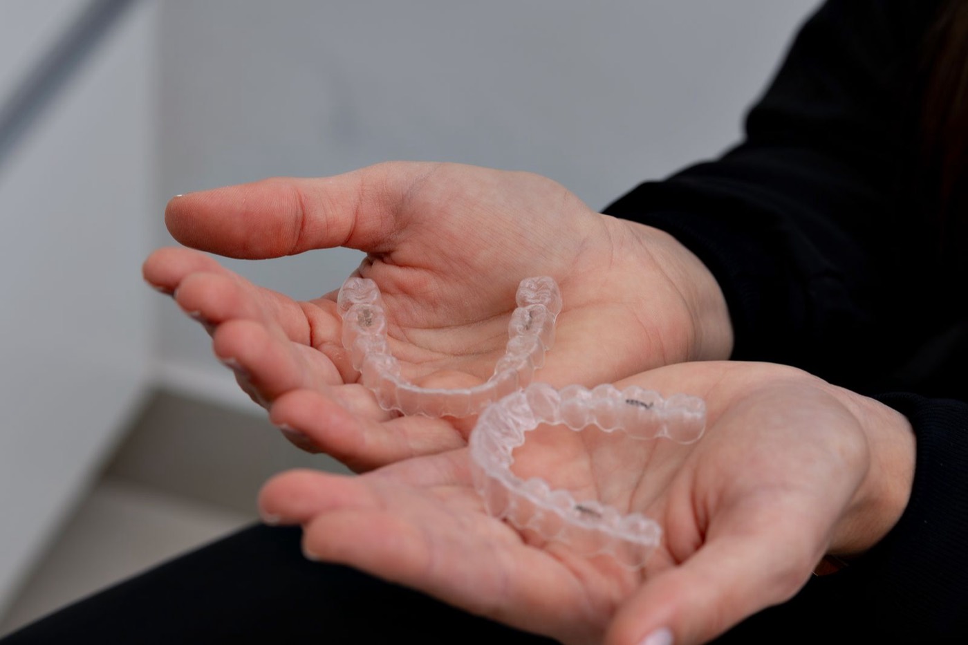 Transparente Aligner-Schienen in den Händen – unsichtbare Zahnkorrektur